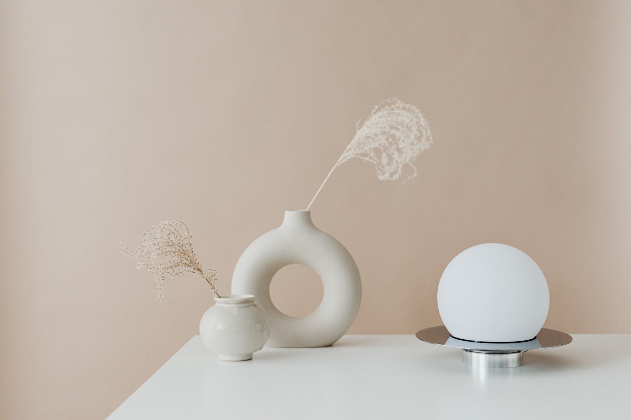 Minimalist arrangement of decorative vases and a modern lamp on a table.